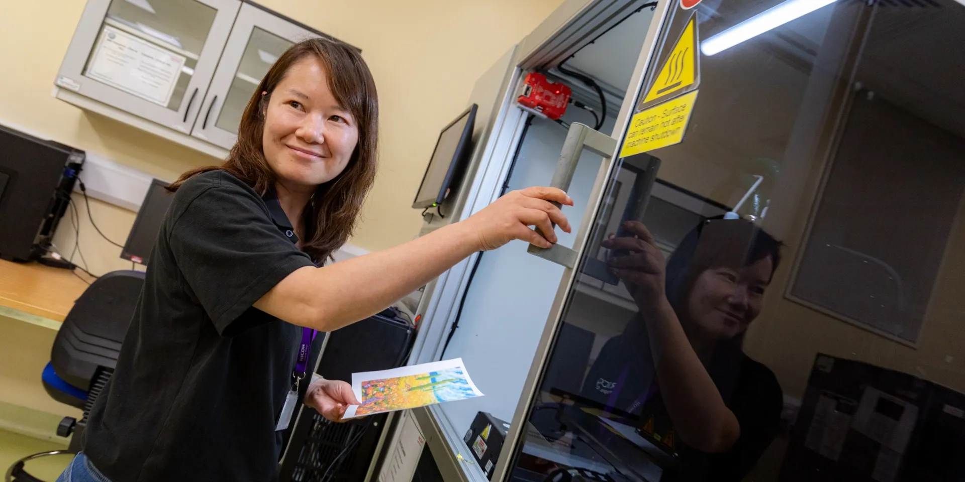 An RPSE employee smiling as she conducts some inkjet testing in the lab and looks at a sample.