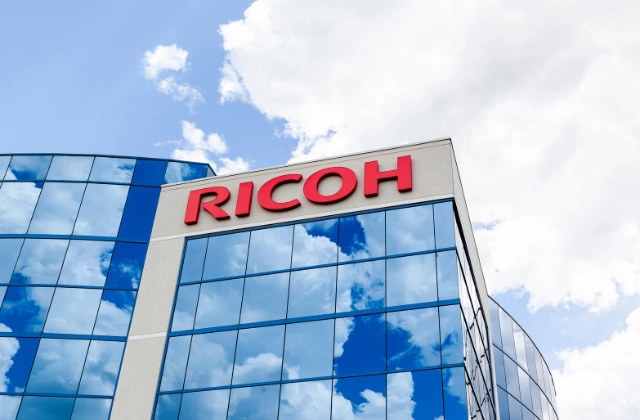 Ricoh Company Limited office building, with the windows reflecting blue sky and clouds.