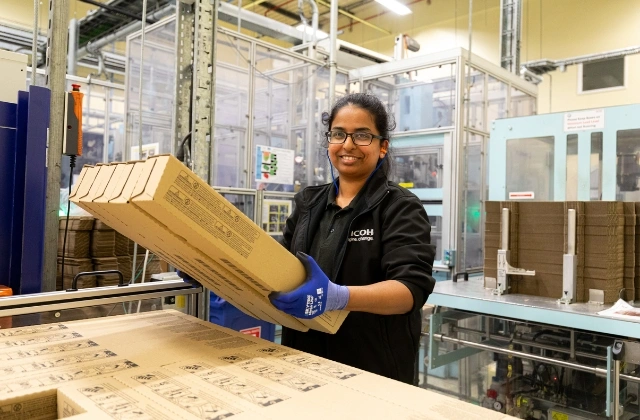 A Ricoh UK Products Ltd employee smiling, as they work in the Gemba.