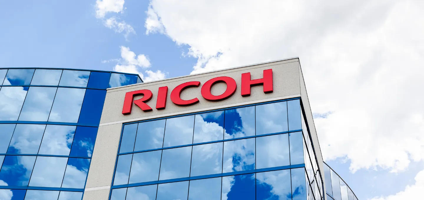 Ricoh corporate building, reflecting the blue sky and clouds.