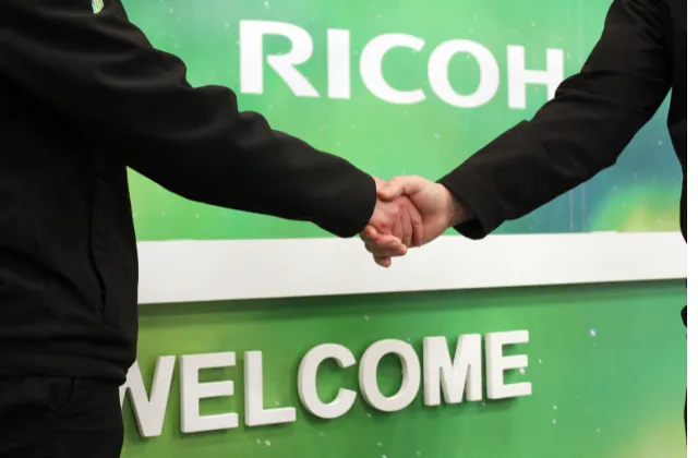 Red fading banner into an inside shot in a production area, with two employees holding and pointing at tablets