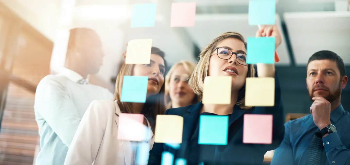 A group of employees engaging in an 'innovation management' conversation, writing on sticky notes.
