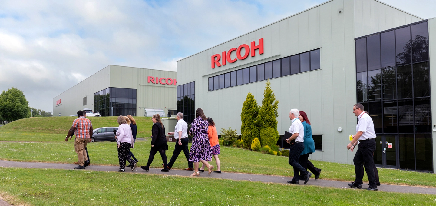 Employees walking in front of Ricoh UK Products Ltd building