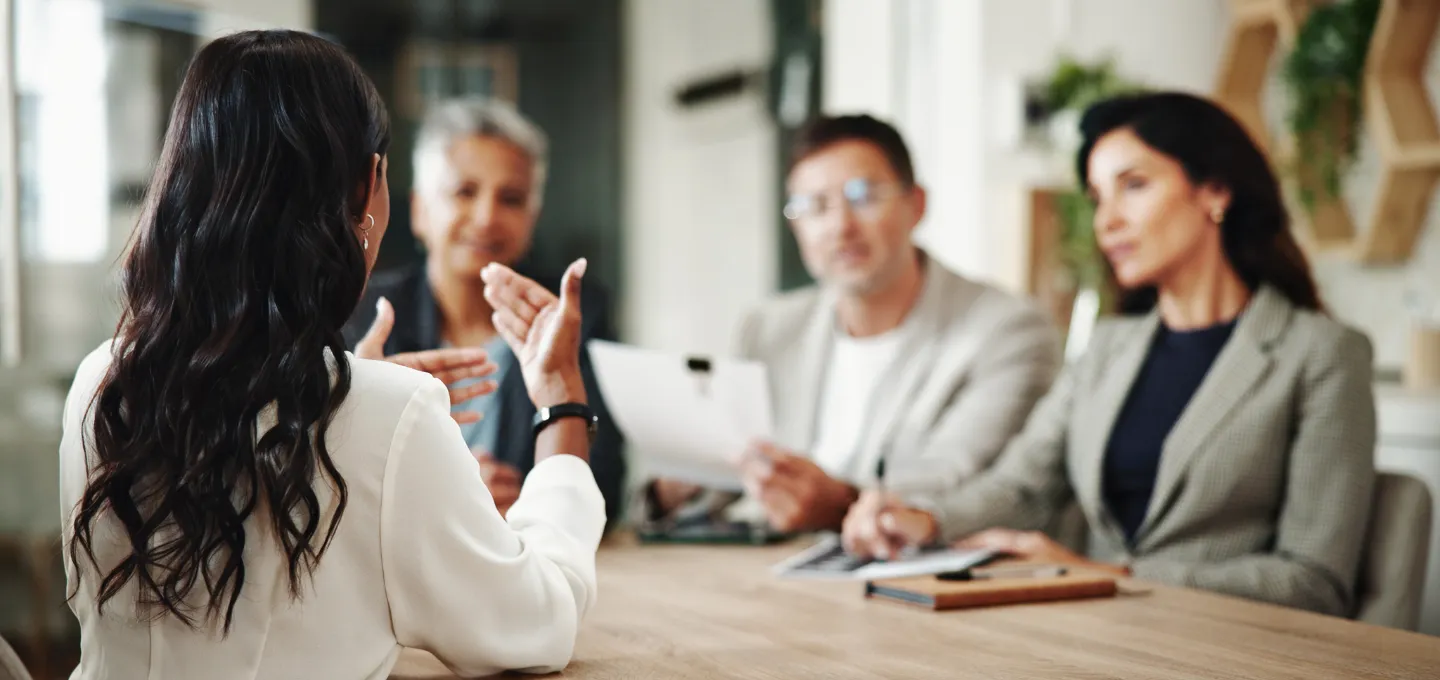 A group of employees in a meeting space, having a conversation regarding risk management. 