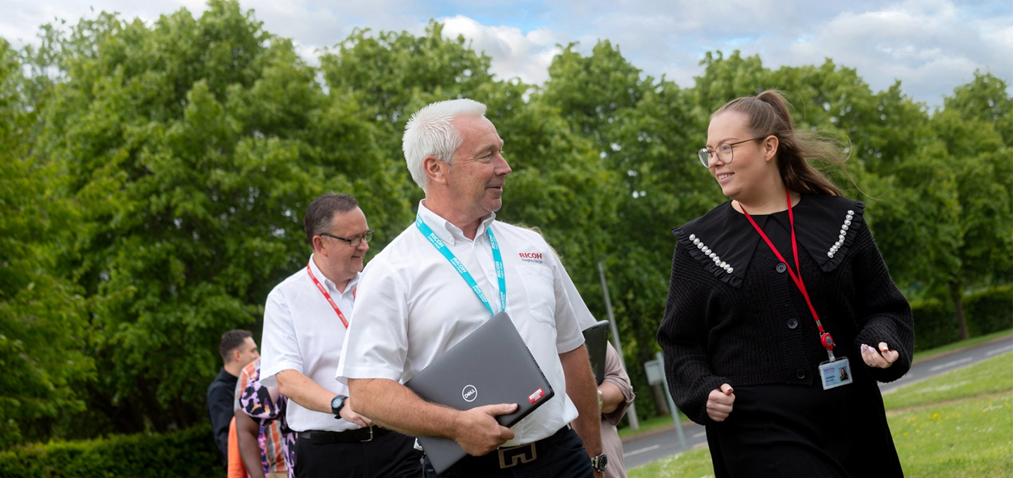 An outdoor area with employees walking and smiling
