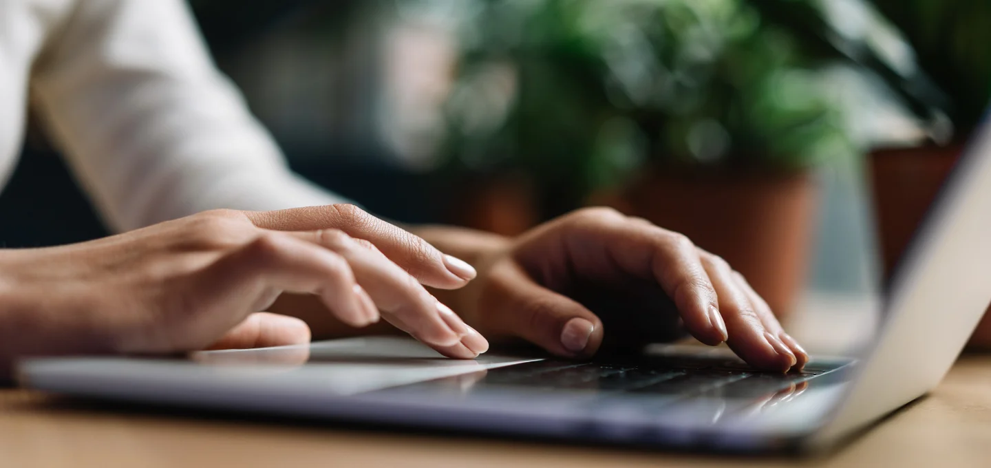 Two hands, typing on a laptop keyboard.
